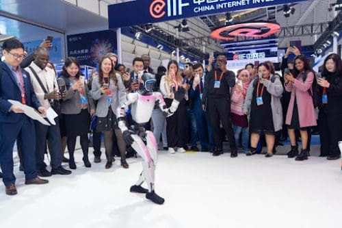 Visitors-to-the-Light-of-Internet-Expo-held-in-Wuzhen-east-China-s-Zhejiang-province-watch-a-humanoid-robot-dance-Nov--scaled.jpg